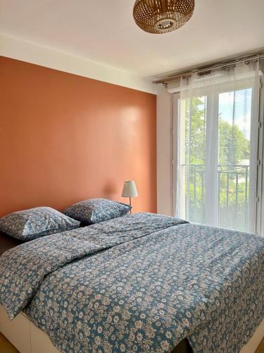une chambre avec un lit avec une couette bleue et une fenêtre dans l'établissement Élégant Appartement Minimaliste entre Paris et Disney, à Noisy-le-Grand