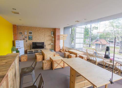 a room with tables and chairs and a large window at Chang Chang Hostel in Chiang Mai