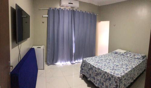 a bedroom with a bed and a blue curtain at Casa Girassol in Camocim