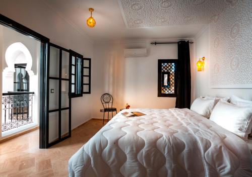 um quarto com uma grande cama branca e uma janela em Riad Tamazgha em Marrakech