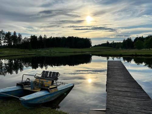 a boat parked next to a dock on a lake at Sodyba Bebrynė in Didviečiai