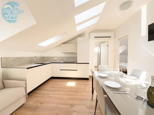 kuchnia z białymi szafkami i stołem z kieliszkami do wina w obiekcie Palazzo Saba Tirabora Short Rent w Trieście