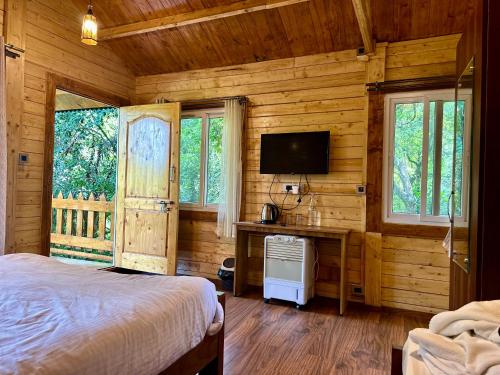 a bedroom with a bed and a desk with a television at Coorg Jungle Mist in Madikeri