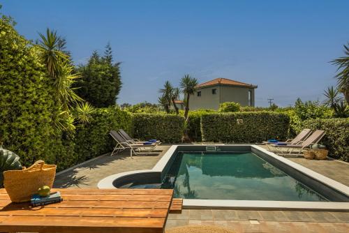 a swimming pool with two chairs and a house at Villa Siora Anna in Skala