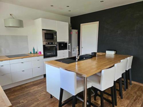 une cuisine avec une table en bois et des armoires blanches dans l'établissement Aux charmes de la campagne, à Venoy