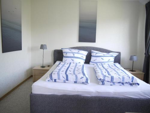 a bed with blue and white sheets and pillows at Haffliebe 2 in Scharbeutz
