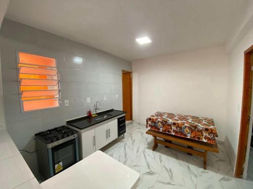 a kitchen with a stove and a bench in it at Casa com Piscina e Churrasqueira ótima localização in Praia Grande