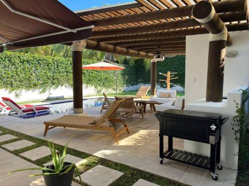 a patio with a grill and chairs and an umbrella at CH036 Casa linda de playa in San José de Guatemala
