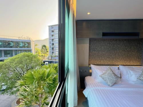 a bedroom with a bed and a view of a building at Modern Urban Living Kamala in Kamala Beach