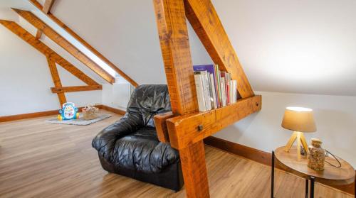 a black leather chair with a book shelf with books at La mylardiere in Piney