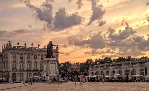 a statue in front of a building with a sunset at Evasion chic, spa et sauna sous les toits in Nancy