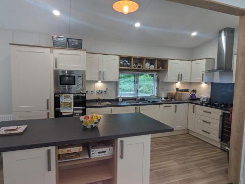 a kitchen with white cabinets and a black counter top at LUXURY STUNNING SENSATION LODGE ON 5 STAR SHOREFIELD COUNTRY PARK New Forest ENTERTAINMENT AND LEISURE PASSES INCLUDED in Milford on Sea