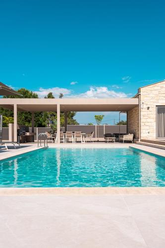 a swimming pool with tables and chairs on a building at Terra Petra Luxury Villas by Travel Pro Services- Vourvourou Halkidiki in Vourvourou