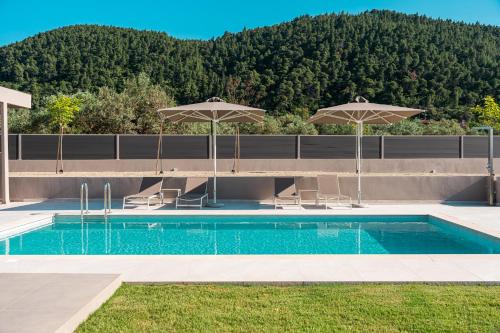 a swimming pool with two umbrellas and chairs and a pool at Terra Petra Luxury Villas by Travel Pro Services- Vourvourou Halkidiki in Vourvourou