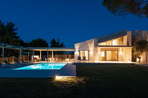 a house with a swimming pool at night at Terra Petra Luxury Villas by Travel Pro Services- Vourvourou Halkidiki in Vourvourou