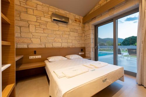 a bedroom with a bed and a stone wall at Terra Petra Luxury Villas by Travel Pro Services- Vourvourou Halkidiki in Vourvourou