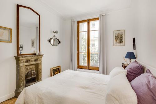 - une chambre avec un lit blanc et une cheminée dans l'établissement GuestReady - Apt cosy près du Jardin des Plantes, à Paris