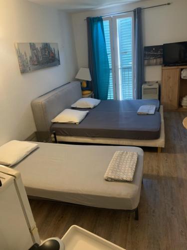 deux lits dans une petite pièce avec une fenêtre dans l'établissement AJACCIO CATHEDRALE AU COEUR DE LA CITEE IMPERIALE POUR 3 a 4 PERS PROCHE DES PLUS BELLES PLAGES ET DE TOUTES COMMODITES PORT A 2MN, à Ajaccio