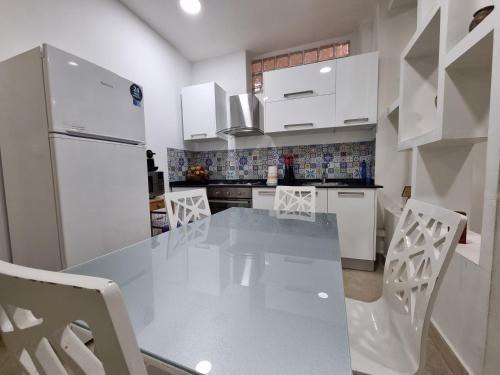 a kitchen with a glass table and white cabinets at Hydra Résidence Privée in Hydra