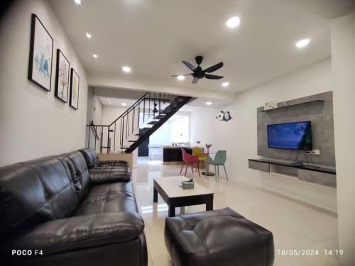 Una sala de estar con un sofá de cuero y un televisor. en MM Homestay, 5pax, Air Putih, Central Town in Kuantan, en Kuantan