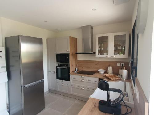 une cuisine avec un réfrigérateur en acier inoxydable et des armoires blanches dans l'établissement l'éden des Baronnies, à Mirabel-aux-Baronnies