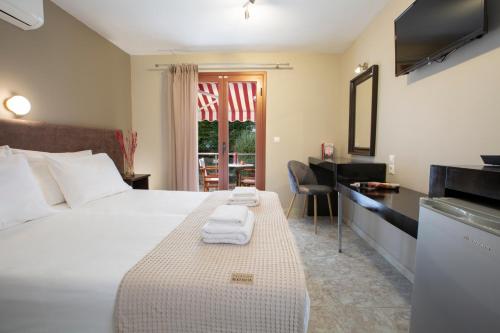 a hotel room with a bed and a desk with towels at Athina résidence in Nydri
