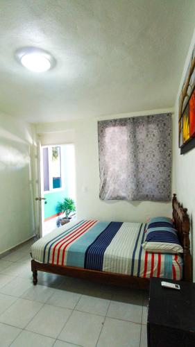 a bedroom with a bed with a colorful striped blanket at Hotel Vias Maya Bacalar in Bacalar