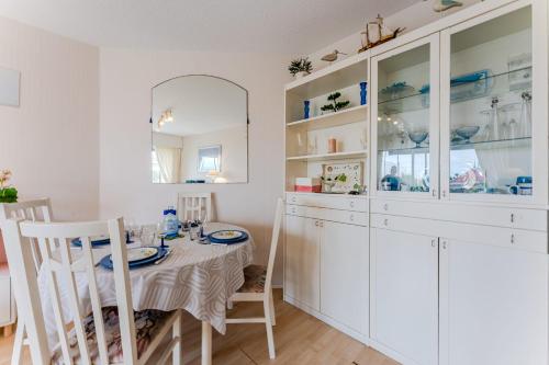 une salle à manger avec une table et des armoires blanches dans l'établissement Appartement Barca - Welkeys, à Arcachon