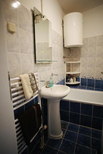 a blue tiled bathroom with a sink and a tub at Lux11 in Sombor