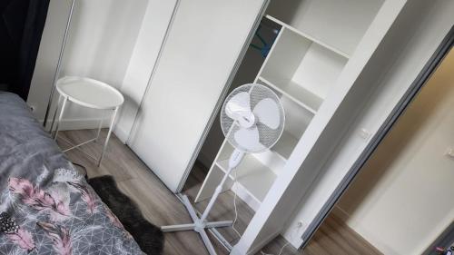une armoire en verre avec un ventilateur à côté d'un lit dans l'établissement Chambre meublée métro 7 La Courneuve 2, à La Courneuve