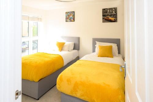 two beds in a room with yellow sheets at Cosy 5 Bedroom House With Parking in Chatham