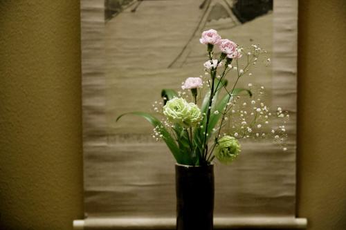 a vase with pink flowers in front of a mirror at Ryokan Wataya in Karatsu