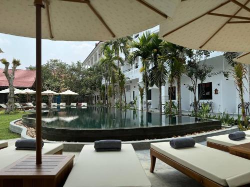 a swimming pool with chairs and umbrellas in a resort at The Urban in Siem Reap
