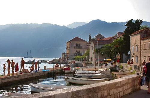a group of people on a beach with boats in the water at Perast apartman "Mika" in Perast