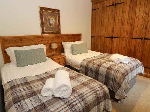 two beds in a hotel room with towels on them at The Steading in Dalmally