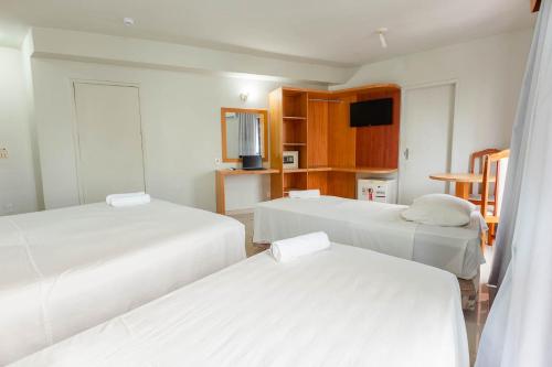 a hotel room with two beds and a television at Rede Andrade Onda Mar in Recife