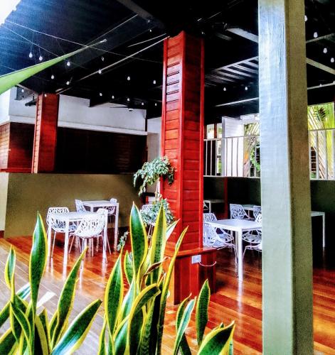 a restaurant with white tables and white chairs and plants at Villa Copthall in Trafalgar