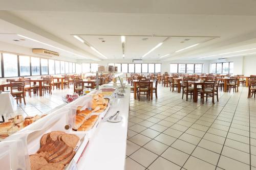 Habitación grande con mesas y sillas con pan a la vista en Rede Andrade Onda Mar en Recife