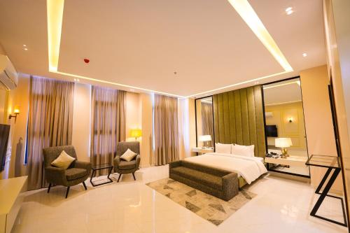 a hotel room with a bed and two chairs at Pavilion Suites - Premium ApartHotel in Bahria Town in Rawalpindi