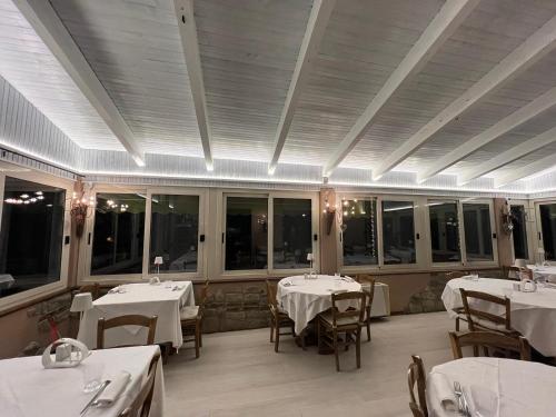 a restaurant with white tables and chairs and windows at VIVERONE LAKE ROOMS in Viverone