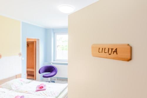 a bedroom with a bed and a sign that reads uka at Apartments Orhideja in Tolmin