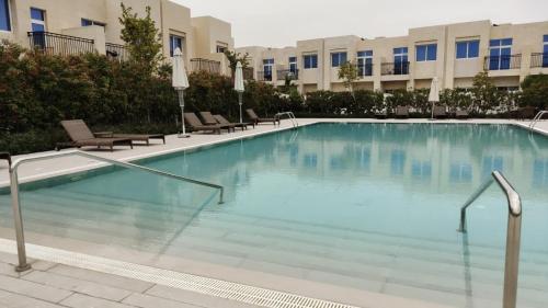 uma grande piscina com cadeiras e um edifício em Damac Hills 2 Retreat- Tranquil Luxe, Beyond City with waterpark no Dubai