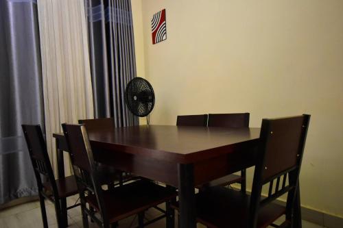 a dining room table with chairs and a fan at ADRIEL HOMES KIGALi in Kigali