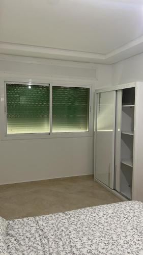 a white room with two windows and a bed at Tanger Relax Appartement in Tangier