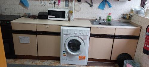 a kitchen with a washing machine and a microwave at Basildon House of Muralist in Basildon