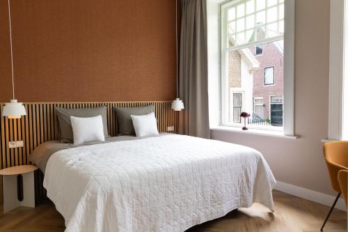 a bedroom with a white bed with a window at Boutique Pastorale in Linschoten