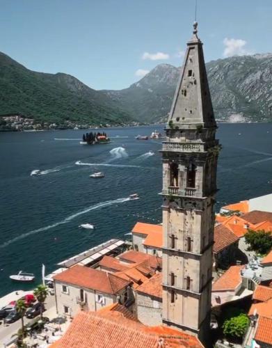 a building with a tower next to a body of water at Perast apartman "Mika" in Perast