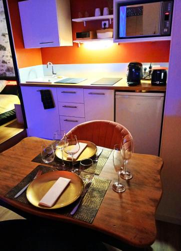 - une table en bois avec 2 assiettes et des verres à vin dans l'établissement La Passionnante Gîte avec Spa privatif, à Saint-Philbert-de-Bouaine