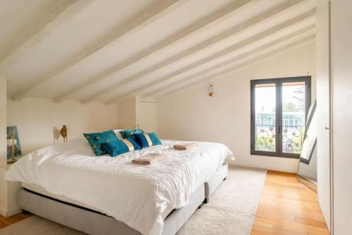 une chambre blanche avec un grand lit avec des oreillers bleus dans l'établissement La belle de Bouliac, à Bouliac