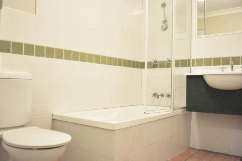 a white bathroom with a toilet and a sink at Meadowbrook Hotel Brisbane in Loganlea